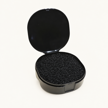 One open black Body Bliss makeup brush cleaner case with its textured insert on warm ivory