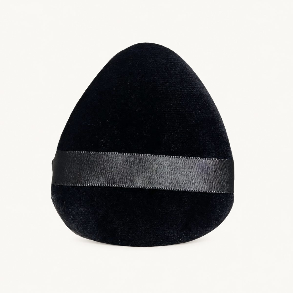 Single black Body Bliss Miracle Blending Facial Makeup Sponge with a horizontal ribbon on a warm ivory background