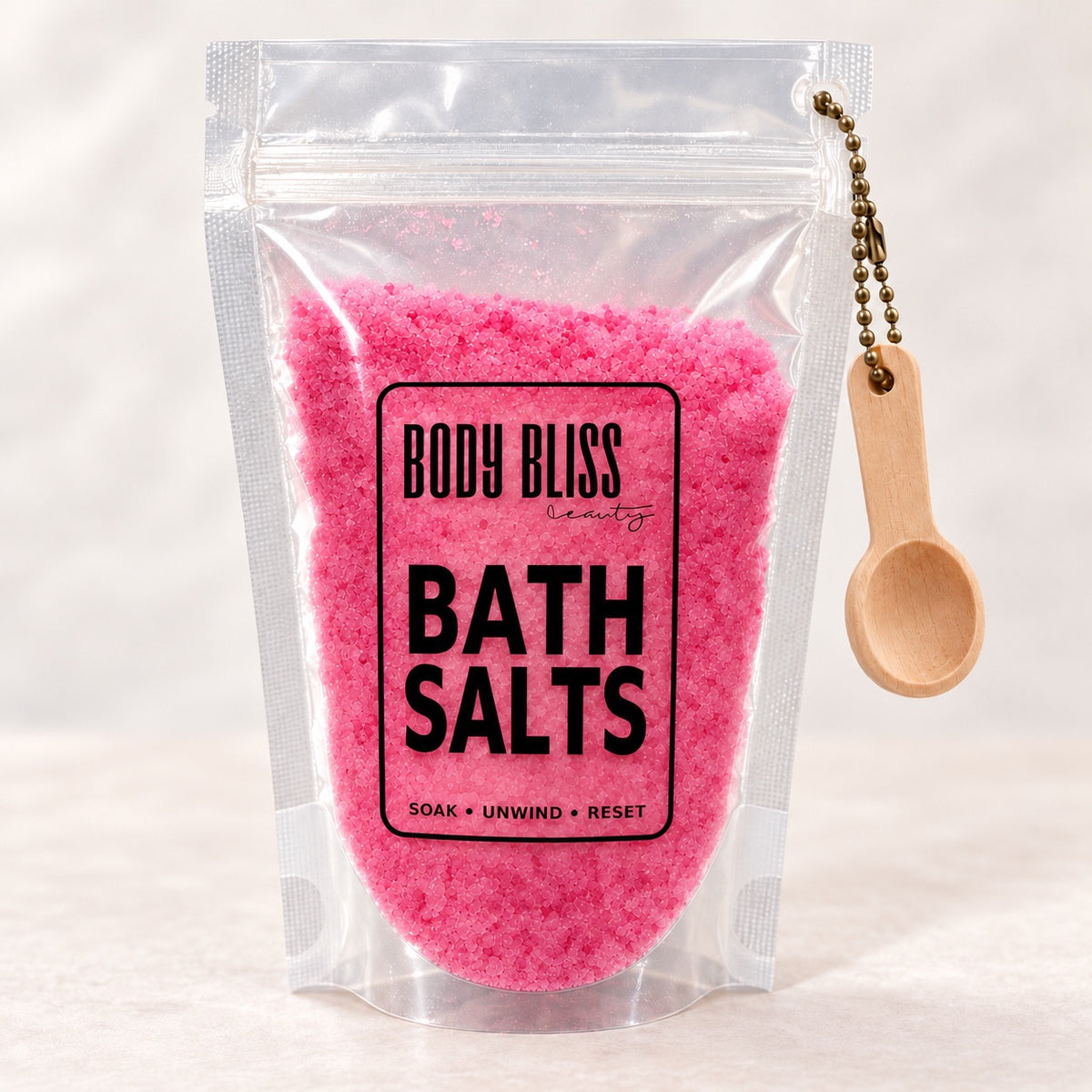 Body Bliss pink bath salts in a clear pouch with wooden scoop