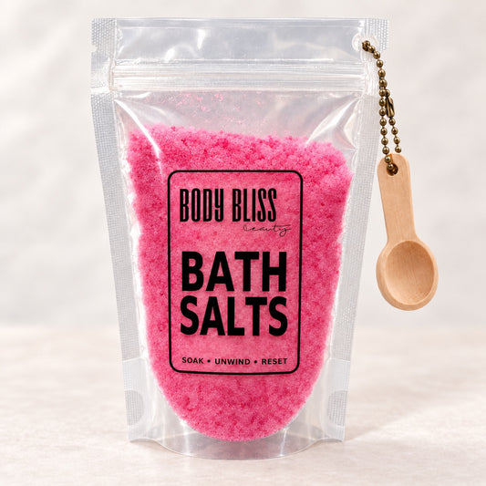 Body Bliss pink bath salts in a clear pouch with wooden scoop