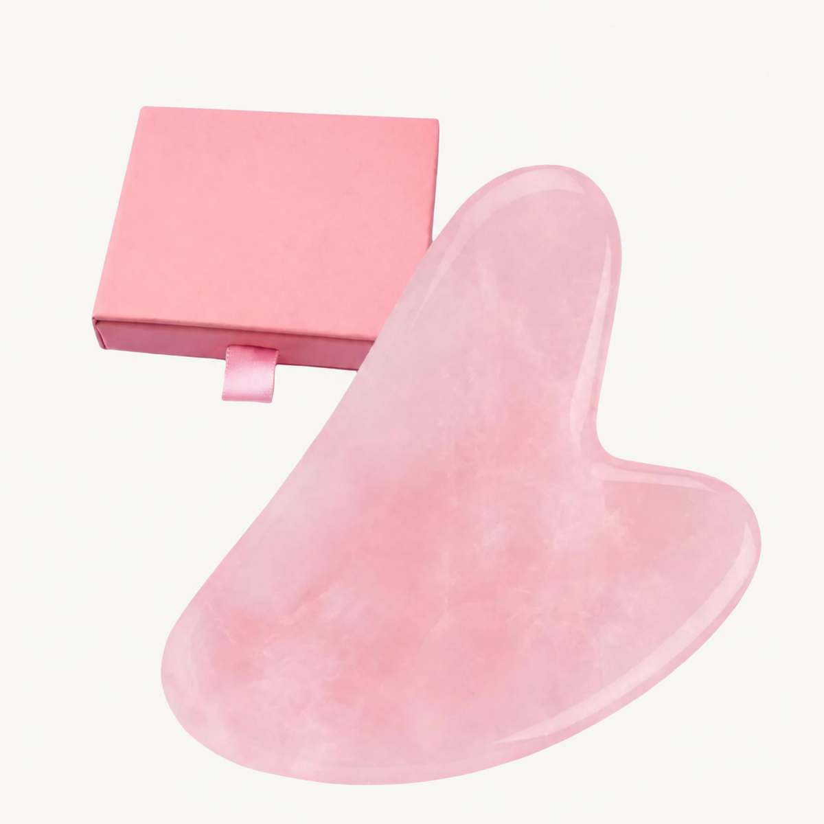 One pink Body Bliss gua sha facial stone with its pink box on a warm ivory background